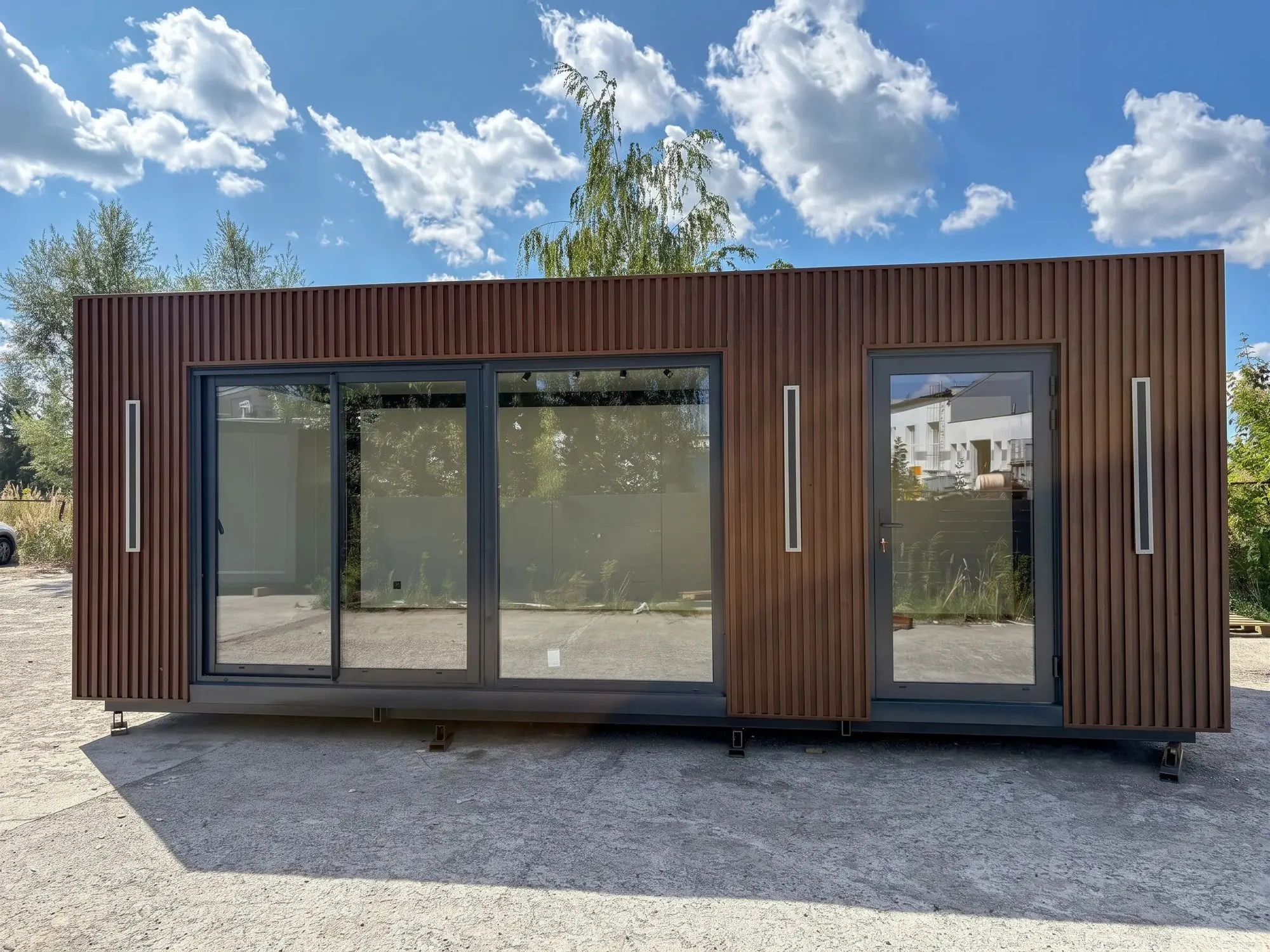 Pavillon mit dunkler Lamellenfassade und breiter Glasfront