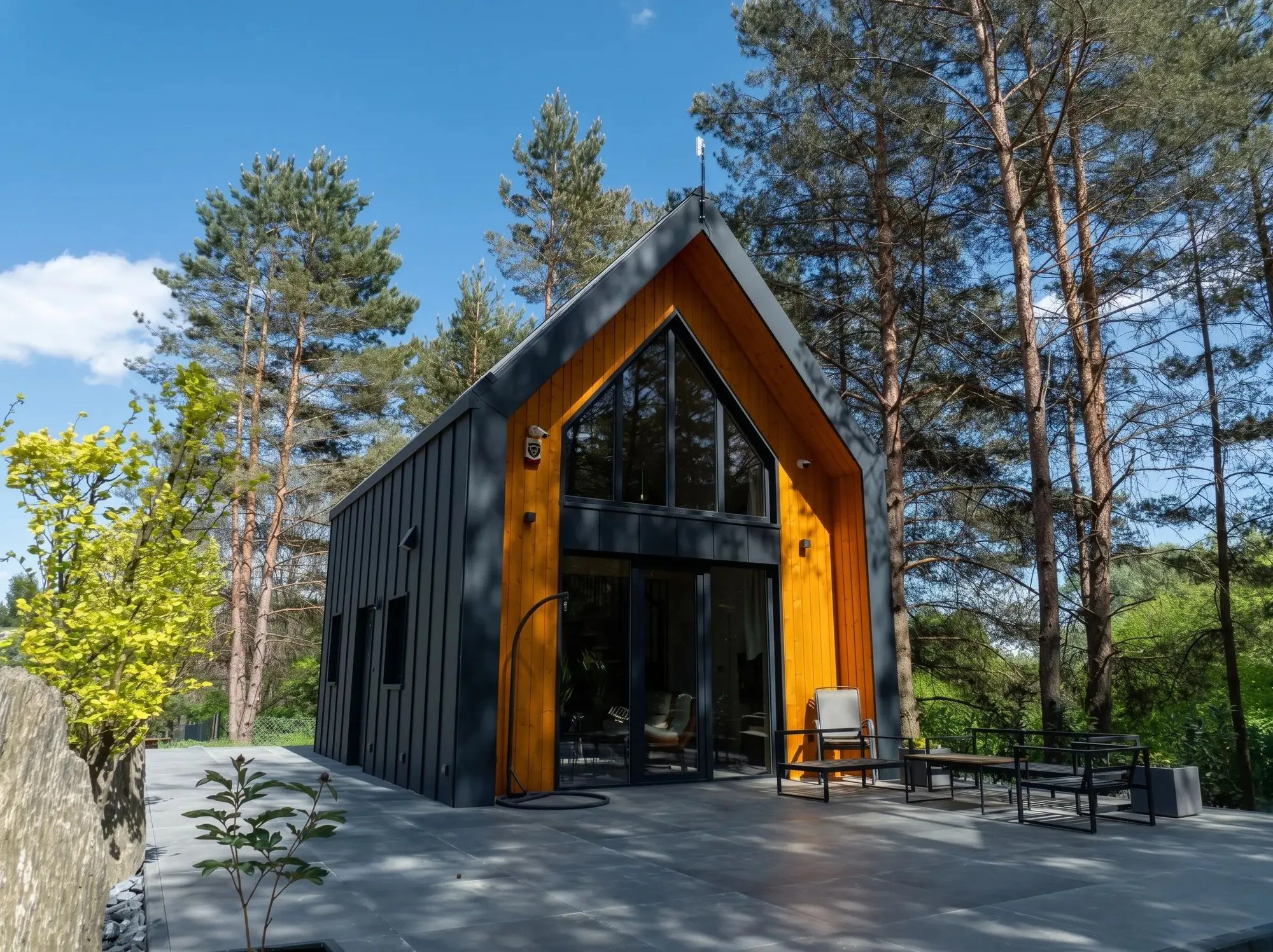 Modulhaus mit Satteldach und verglastem Holzgiebel zwischen Kiefern